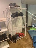 Metal rack shelving unit with 4 wire mesh shelves holding boxing and martial arts equipment such as helmets and gloves.