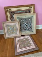 Four Native American themed framed wall art pieces grouped on floor showing large, medium, and two small art pieces