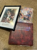 Framed Larry Bird autographed photo next to sports card album and bag of cards
