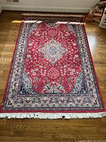 Top-down photo of the red traditional area rug showing full front face with central medallion and fringe.