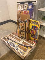Photo showing the stacked boxes of the K-Line Alaskan Train Set, Matchbox Rapid Shot Car Set, and Motor City Deluxe Play Track Set on floor against wall.