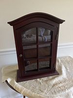 Front view of the closed wood and glass display cabinet on a table.