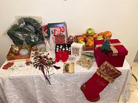Overview of the Christmas ornaments, garlands, stocking, boxes, and wrapping materials arranged on a table with a white cloth.