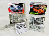 Photo of both AMT Ertl model car kits including the 1960 Ford Starliner and 1995 Toyota Supra boxes with plastic parts and instructions visible.