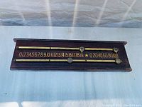 Front view of vintage dark wood billiards score board showing brass slider and numbered scoring track