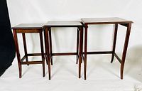 Three darkwood nesting tables side by side showing size variation and design