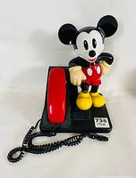 Front view showing Mickey Mouse figure with red handset and black coiled cord on black base with sticker labeled 735 14x10.