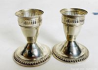 Pair of sterling silver weighted candlesticks with beaded base and pierced gallery detail, shown side view.