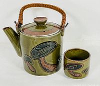 Full view of mushroom design pottery tea pot and matching cup, showing size and colors