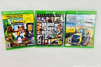 Three Xbox One video game cases: Crash Bandicoot 3, Grand Theft Auto V, and Farming Simulator 17 arranged side by side