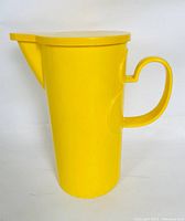 Side view of bright yellow Dansk pitcher showing handle, spout, and flat top lid.