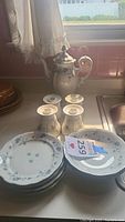 Image showing the tea pot, four small candle holders placed upside down, four plates stacked, and three bowls.