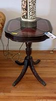 Full view of mahogany side table showing claw feet and overall table shape with decorative leather top.