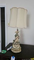 Full view of vintage lamp with sculpted children on metal base and fabric shade