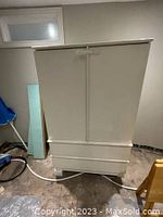 Front view of white wardrobe cabinet with two doors and two drawers at base, showcasing overall design and locking latch on doors.