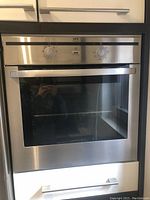 Front view of stainless steel built-in wall oven with two control knobs and glass window door.