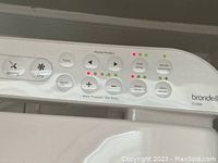 Close-up of right side control panel showing LED indicators and labeled buttons for water pressure, temperature, nozzle position, dryer and eco mode