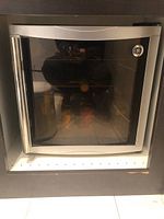 Front view of GE Wine Fridge with glass door showing the stainless steel frame and bottle shelving inside.