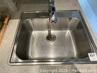 Top view of a rectangular stainless steel sink with deep basin and drain.
