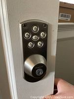 Electronic deadbolt keypad side installed on door with satin nickel finish and key slot below keypad.