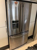 Front exterior view of stainless steel LG French door refrigerator with external ice and water dispenser and bottom freezer drawer