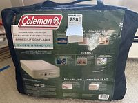 Photo of front side of Coleman air mattress package in dark green carrying bag, shows brand and product name.