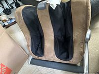 Side view of brown and black Human Touch leg massager with fabric upholstery and leg openings.