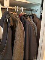 Multiple men's jackets and coats on hangers showing variety of colors and fabrics.