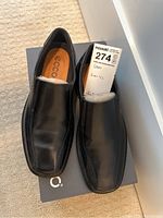 Pair of black leather men's shoes from Ecco sitting on a box, upper and side view showing slight creasing and detailing.