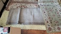 Multiple rugs and mats layered on hardwood floor showing size, texture, and color.