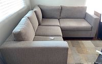 L-shaped two-piece sectional sofa in light gray woven fabric placed in corner