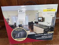 Box packaging of Sanus full-motion TV wall mount showing front with promotional image of TV mounted in living space and product details.