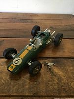 Front three-quarter view of green metal Team Lotus key-wind race car with key placed beside it