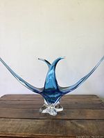 Front view of the blue glass vase showing sweeping curved arms and clear base.
