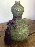 Overall view of the green celadon crackle double gourd vase with visible crackle lines and braided purple tassel with tassels