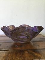 Side view of purple and yellow crinkled art glass bowl showing wavy rim and color blending