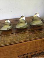 Three asymmetrical, organic rounded triangular metal bowls arranged side by side on a wooden surface.
