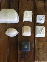 Top view of all seven jewelry boxes arranged on wood surface showing varying shapes and light cream colors with one dark box.