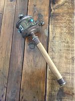 Full view of the prayer wheel with wooden handle lying on rustic wood surface