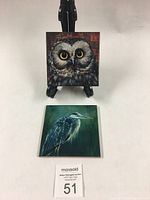 Both coasters together, showing owl and heron images, with a MaxSold auction card for scale.