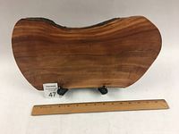 Front view of apple wood charcuterie board with natural irregular edges shown with a ruler indicating approximately 15 inches in width.