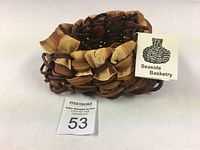 Front view of bull kelp woven basket showing braided rim and natural coloration with Seaside Basketry tag
