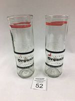 Pair of clear glass beer glasses with printed Original Organic Lager branding, showing the front side with red and black text.