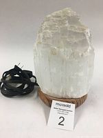 Himalayan salt lamp unplugged showing natural white salt crystal and black electrical cord on wooden base.