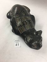 Full view of Mexican clay cat sculpture showing its shape, painted details on the back and some surface wear.