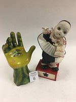 Musical clown figurine and magic hand sculpture shown side by side on a white background with a lot number card.
