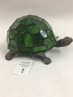 Photo of the turtle lamp showing the bronze-tone metal turtle base and green stained glass shell shade from a side angle.