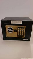 Front view of the black metal safe showing gold keypad panel and key lock
