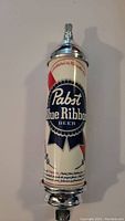 Front view of Pabst Blue Ribbon beer tap handle showing logo and colors