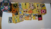 Broad view of Pokemon cards laid out next to a Darkrai collectible tin
